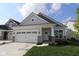 Charming home featuring a two-car garage, stone accents, and a well-manicured lawn on a sunny day at 10604 Maidenhair Dr, Indianapolis, IN 46239