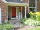 Inviting covered front porch with summer decorations, flower planters, and a red door with glass panel at 1067 Barley Cir, Carmel, IN 46032