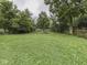 Large, lush backyard with green groundcover and mature trees beyond a wooden fence at 1603 S Morgantown Rd, Greenwood, IN 46143