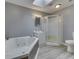 Bright bathroom featuring a skylight, tiled floors, vanity sink, shower, and a large soaking tub at 1603 S Morgantown Rd, Greenwood, IN 46143