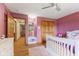 Bedroom with pink walls, wood floors, and white crib at 1682 S Fox Cove Blvd, New Palestine, IN 46163