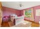 Bedroom with pink walls, plush rug, window, and white crib at 1682 S Fox Cove Blvd, New Palestine, IN 46163