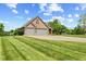 Side view of a brick home with a spacious three-car garage and well-manicured lawn at 1682 S Fox Cove Blvd, New Palestine, IN 46163