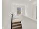 Well-lit hallway with a view of a window, black railing, and carpeted stairs at 16929 Sandhurst Pl, Westfield, IN 46074