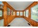A sunroom lined with wood paneling and multiple windows offer a view of the surrounding landscape at 171 Nursery Rd, Anderson, IN 46012