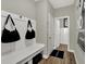 Functional mudroom with built-in bench, coat hooks, and a welcome mat leading to a nearby bathroom at 19838 Moorpark Lndg, Noblesville, IN 46062
