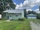 Lovely single story home with green siding, bright white trim, and a detached two car garage at 2473 N Goodlet Ave, Indianapolis, IN 46222