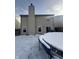View of the back of the home with a large chimney, back patio, and a trampoline covered in snow at 2734 Mingo Ct, Indianapolis, IN 46217