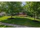 Beautifully landscaped front yard with mature trees providing shade and curb appeal to the brick home at 2901 Hazel Foster Dr, Carmel, IN 46033