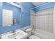 Bathroom in light blue with white tiles featuring a bathtub, toilet, mirror, and sink at 2920 Bloomsbury S, Greenwood, IN 46143