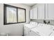 Functional laundry room with front loading machines, overhead cabinet storage, and natural light at 3090 N County Road 800 E Rd, Brownsburg, IN 46112