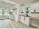 Open kitchen area has white cabinets, light countertops, and stainless steel sink beneath the window with backyard view at 3712 S Kealing S Ave, Indianapolis, IN 46237