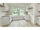 Bright kitchen has white cabinets and light countertops, two windows, and wood flooring at 3712 S Kealing S Ave, Indianapolis, IN 46237