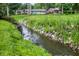 Scenic flowing creek with rocks running through lush backyard with neighborhood homes in background at 4070 Serenity Way Ct, Greenwood, IN 46142