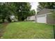 Spacious backyard featuring a detached garage, lush lawn, and mature trees providing ample shade and privacy at 4903 E Naomi St, Indianapolis, IN 46203