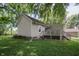 Back exterior view with a wooden deck and lush green surroundings, steps leading down to the yard at 4903 E Naomi St, Indianapolis, IN 46203
