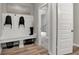 A mudroom with a white bench, hooks, wood floors, and an open doorway at 5343 Pelion Pl, McCordsville, IN 46055