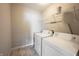 A clean laundry room features a white washer and dryer set with overhead shelving for convenient storage at 6218 N Woodside Ct, McCordsville, IN 46055