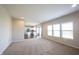 Bright living room featuring neutral walls, carpet, and an open-concept design leading to a well-lit kitchen at 6218 N Woodside Ct, McCordsville, IN 46055