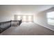 Spacious loft area with plush carpeting, ample natural light from multiple windows, and views of the staircase at 6218 N Woodside Ct, McCordsville, IN 46055