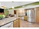 Bright kitchen with tiled floors, wooden cabinets, granite counters, and stainless fridge at 6439 Bower Dr, Indianapolis, IN 46241