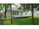 Backyard with a deck, lush green grass, mature trees, and a view of the house at 6816 Minnow Dr, Indianapolis, IN 46237