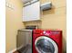 Well-organized laundry room features a modern red washing machine and gray dryer with storage above at 770 Viewpoint Dr, Plainfield, IN 46168