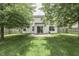The backyard showcases a covered patio and lush lawn bordered by mature trees at 7914 Willow Wind Cir, Indianapolis, IN 46239