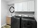Well-lit laundry room features modern washer and dryer, white cabinets, vanity and decorative mirror at 8030 5 Points Rd, Indianapolis, IN 46259