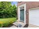 Well-manicured lawn, flowerbed, and townhome entrance with a green front door and attached garage at 9046 Sparta Dr, Fishers, IN 46038