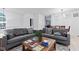 Bright living room features a gray sectional sofa, wooden coffee table with books, and views into the dining room at 9046 Sparta Dr, Fishers, IN 46038