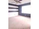 Neutral bedroom with carpet, a ceiling fan, and large window with a black and white striped accent wall at 922 Eagle Brook Dr, Shelbyville, IN 46176