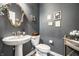 Elegant powder room with pedestal sink, decorative mirror, and stylish dark gray walls at 9407 Casey Rd, Pendleton, IN 46064