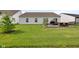 This backyard features a brick patio with outdoor seating, a grill, lush green grass, and a young, decorative pine tree at 9858 Bryce Blvd, Pendleton, IN 46064