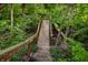 Tranquil backyard featuring a wooden bridge and stairs, surrounded by lush greenery at 11544 Crestwood Ct, Indianapolis, IN 46239