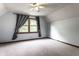 Cozy bedroom featuring neutral carpet, a window with decorative curtains and a ceiling fan at 11544 Crestwood Ct, Indianapolis, IN 46239