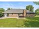 Back exterior showcasing the brick house, patio, landscaped lawn, and a hot tub at 12661 Doe Ln, Indianapolis, IN 46236
