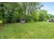 Large backyard with a storage shed, lush grass, mature trees, and a hot tub at 12661 Doe Ln, Indianapolis, IN 46236