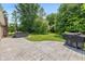 Private backyard featuring a concrete patio, lush lawn, mature trees, and a hot tub at 12661 Doe Ln, Indianapolis, IN 46236