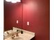 Bathroom with a white sink, mirror, and a vibrant red wall, offering a modern and stylish look at 1273 Helford Ln, Carmel, IN 46032