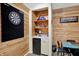 Basement kitchenette with mini-fridge, dart board, wood accent wall and adjacent dining table at 1377 Sedona Dr, Carmel, IN 46032