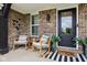 Inviting front porch featuring rocking chairs, stylish decor, brick facade, and a welcoming entrance at 1414 W Springhurst Blvd, Greenfield, IN 46140