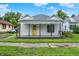 Charming single-story home with white painted brick, yellow door, covered front porch, and well-maintained yard at 1418 W 5Th St, Anderson, IN 46016