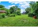 Expansive lawn and verdant trees surround this two-story home with dark siding and a charming red door at 1418 W 5Th St, Anderson, IN 46016