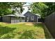 Backyard view showing house, shed, door, and lush green lawn with privacy fence at 1504 Manhattan Ave, Indianapolis, IN 46241