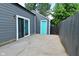 View of backyard concrete pad with gray siding, light fixture, sliding door, and turquoise door with black fence at 1504 Manhattan Ave, Indianapolis, IN 46241
