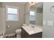 Bathroom vanity with grey cabinets, white counter and sink, a large mirror, a toilet, and a window at 1504 Manhattan Ave, Indianapolis, IN 46241