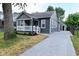 View of home with gray siding, covered porch, gravel driveway, and a detached garage at 1504 Manhattan Ave, Indianapolis, IN 46241