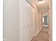 Hallway featuring double closets with bifold doors and white trim leading into another bedroom and wood-look flooring at 1504 Manhattan Ave, Indianapolis, IN 46241