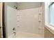 Bright bathroom featuring a white shower and tub with built in shelving and a window for natural light at 1504 Manhattan Ave, Indianapolis, IN 46241